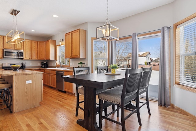 kitchen featuring a sink, stainless steel appliances, an inviting chandelier, and light wood-style flooring