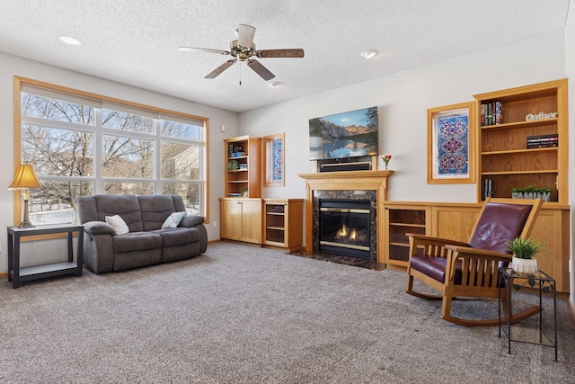 carpeted living room with a high end fireplace, a textured ceiling, and ceiling fan