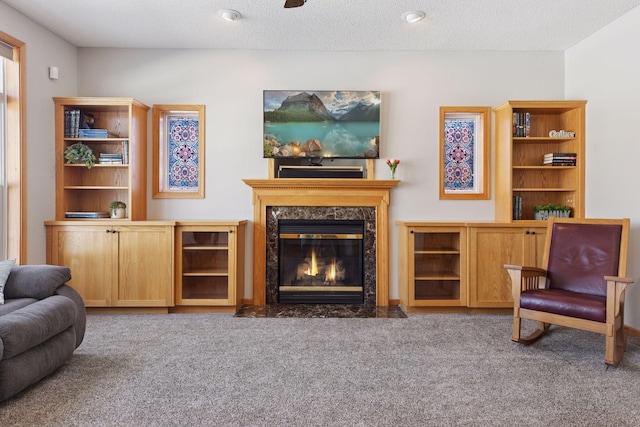 living area featuring a high end fireplace, a textured ceiling, and carpet floors