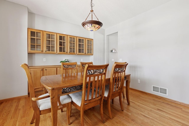 dining area with baseboards, visible vents, and light wood finished floors