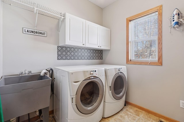 laundry area featuring washing machine and dryer, cabinet space, baseboards, and a sink