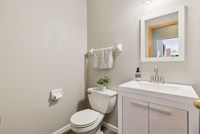 bathroom with toilet, vanity, and baseboards