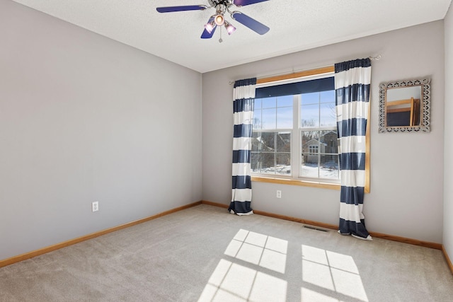 carpeted spare room with visible vents, ceiling fan, a textured ceiling, and baseboards