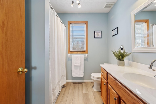 full bath featuring vanity, wood finished floors, visible vents, a textured ceiling, and toilet