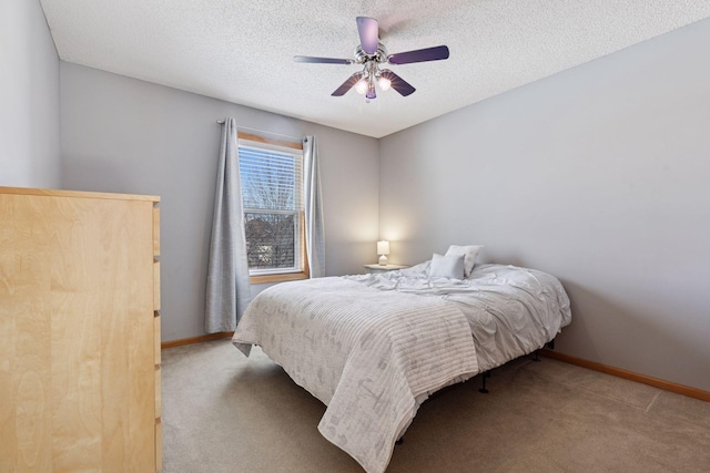 bedroom with a textured ceiling, baseboards, carpet, and a ceiling fan