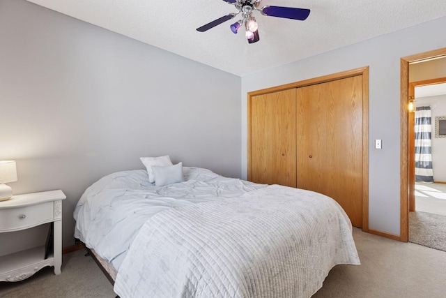 carpeted bedroom featuring a closet, a textured ceiling, baseboards, and ceiling fan