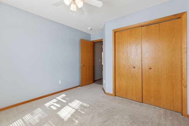 unfurnished bedroom featuring ceiling fan, baseboards, carpet flooring, a closet, and a textured ceiling