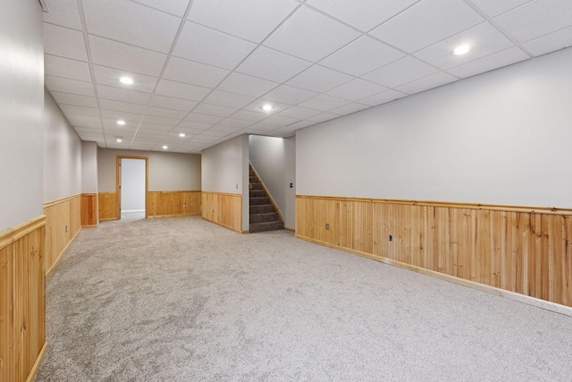 carpeted empty room with a wainscoted wall, recessed lighting, stairway, and wooden walls