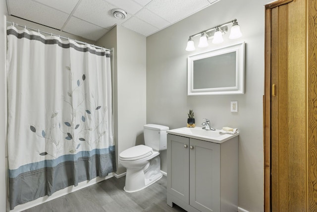 bathroom with vanity, wood finished floors, a drop ceiling, curtained shower, and toilet