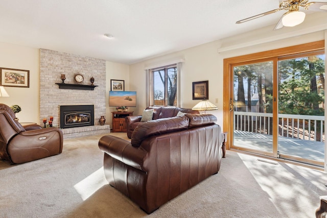 living area featuring a fireplace, a ceiling fan, and carpet flooring