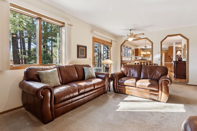 living room featuring arched walkways, carpet flooring, a notable chandelier, and baseboards