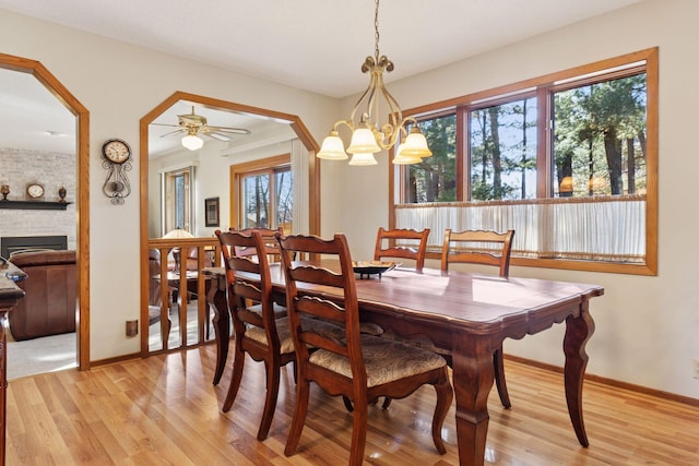 dining space featuring baseboards, arched walkways, and light wood-style floors