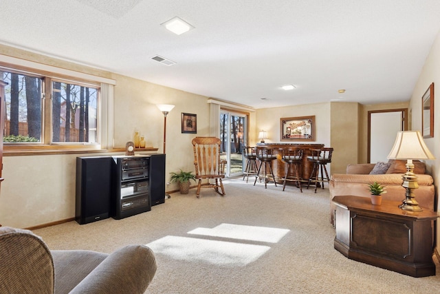 carpeted living area with baseboards, visible vents, and a dry bar