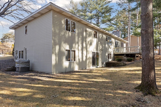 exterior space with a deck, a yard, central AC unit, and a chimney