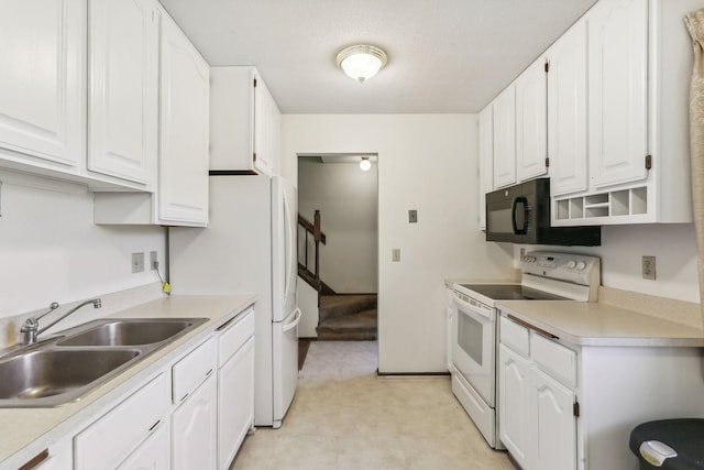 kitchen with white appliances, white cabinetry, light countertops, and a sink