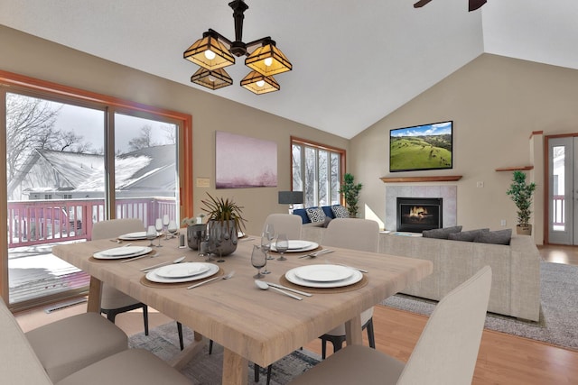 13413 Pine View Pl, Lindstrom, MN 55045 - dining room featuring a ceiling fan, light wood-style flooring, a tiled fireplace, and high vaulted ceiling