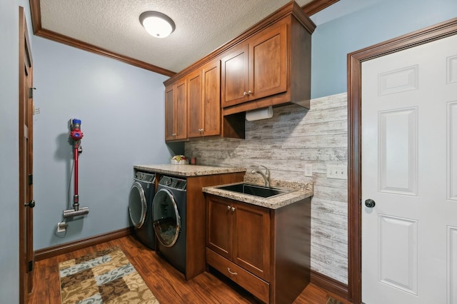 clothes washing area featuring dark wood-style flooring, cabinet space, a sink, and washing machine and clothes dryer