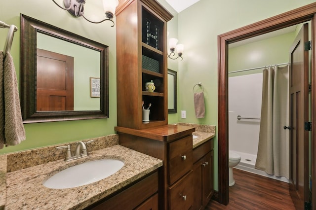 bathroom with toilet, a shower stall, wood finished floors, and vanity