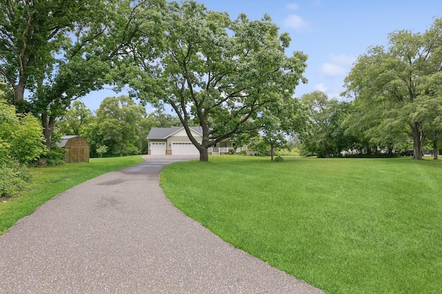 view of community with a garage, a yard, an outdoor structure, and a shed