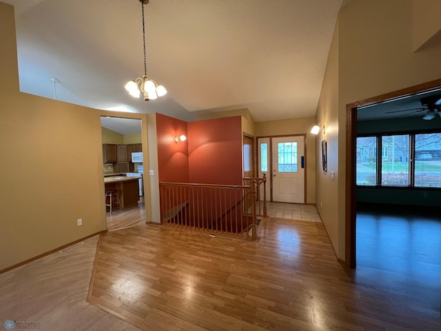 unfurnished dining area with light wood finished floors, a notable chandelier, baseboards, and vaulted ceiling