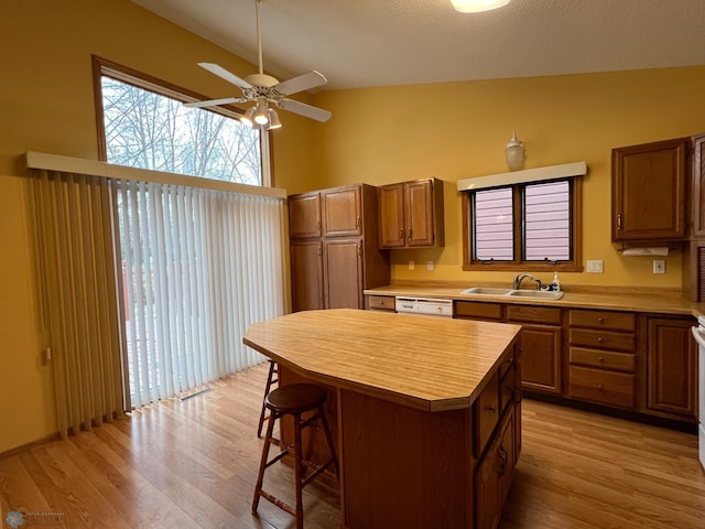 kitchen with a sink, a breakfast bar area, light countertops, and vaulted ceiling