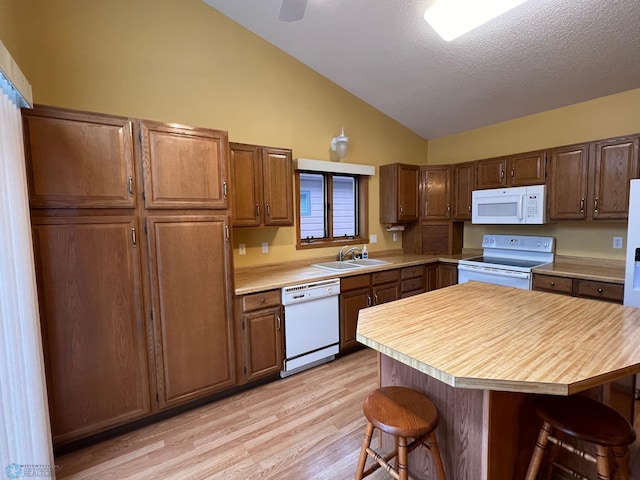 kitchen with white appliances, a breakfast bar area, light countertops, and lofted ceiling