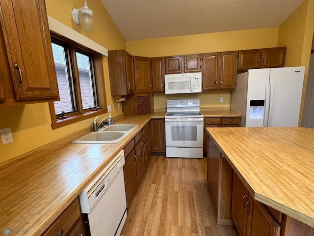 kitchen with lofted ceiling, light wood-style floors, white appliances, wood counters, and a sink