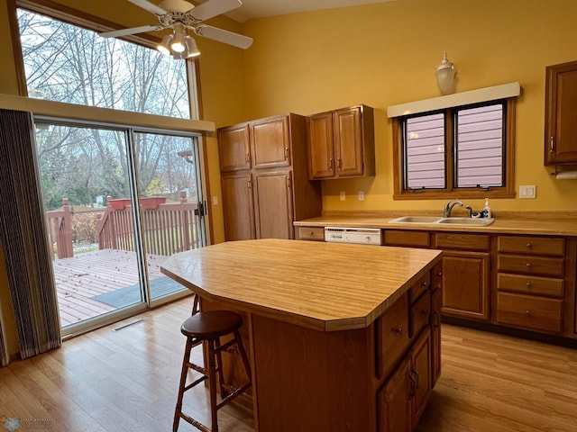 kitchen featuring high vaulted ceiling, a sink, light wood-style floors, light countertops, and dishwasher