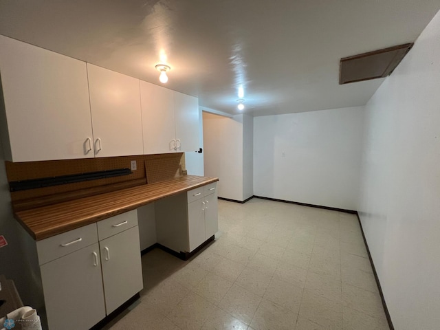 kitchen with white cabinetry, light floors, baseboards, and butcher block counters