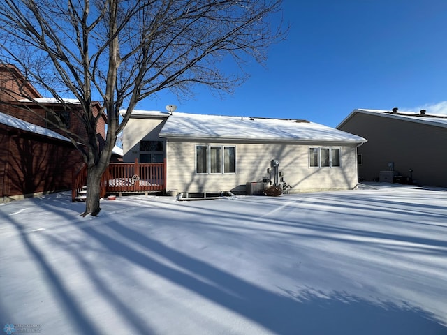 snow covered back of property with a deck