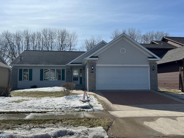 ranch-style house featuring decorative driveway, brick siding, and an attached garage