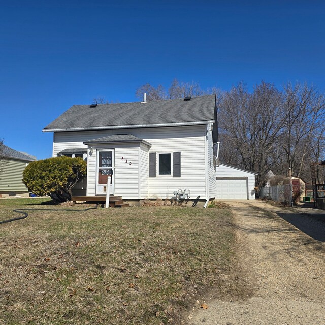 bungalow-style house with a front lawn, a garage, and an outdoor structure