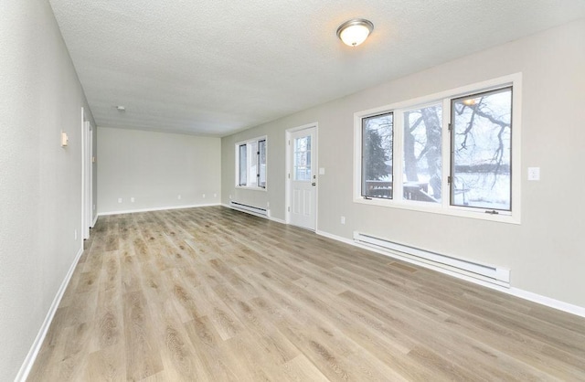 unfurnished living room featuring a baseboard radiator, baseboards, light wood-style flooring, and a textured ceiling