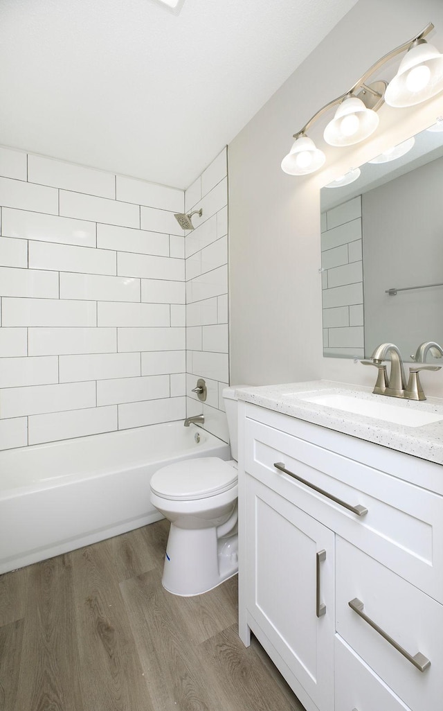 bathroom featuring  shower combination, vanity, wood finished floors, and toilet