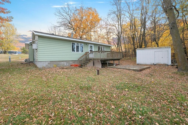 rear view of property featuring stairs, a yard, a storage shed, and a wooden deck