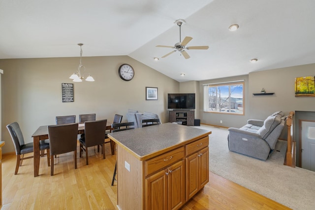 kitchen featuring a kitchen island, open floor plan, pendant lighting, lofted ceiling, and light wood-style flooring