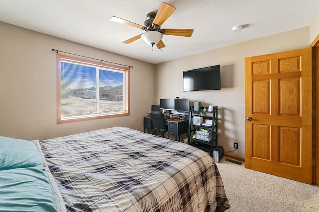 carpeted bedroom featuring baseboards, visible vents, a textured ceiling, and a ceiling fan