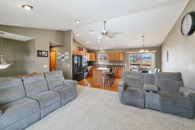 living room with light wood-style flooring, a ceiling fan, and vaulted ceiling