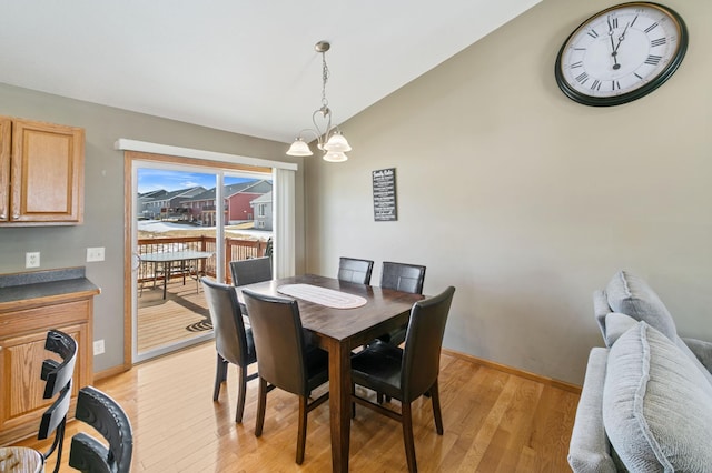 dining room with a notable chandelier, baseboards, light wood-type flooring, and lofted ceiling