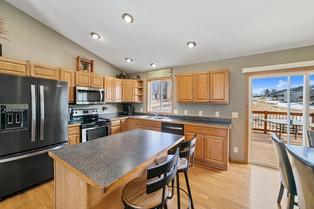 kitchen featuring lofted ceiling, a sink, stainless steel appliances, dark countertops, and a kitchen breakfast bar