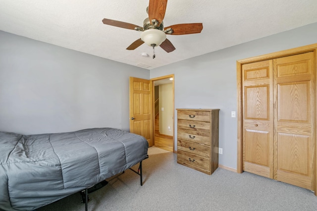 bedroom featuring baseboards, light colored carpet, a textured ceiling, and a ceiling fan