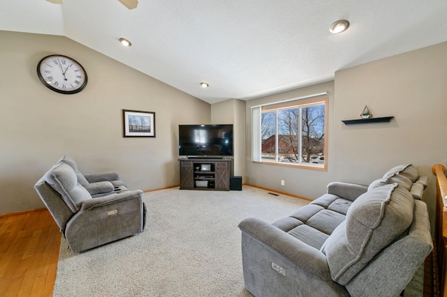 living room with a ceiling fan, lofted ceiling, visible vents, and baseboards