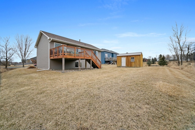 rear view of house featuring an outdoor structure, stairway, a lawn, and a wooden deck