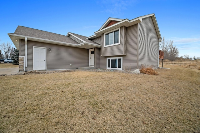 view of front of home with a front yard and a shingled roof