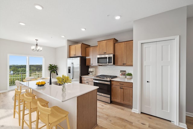 kitchen with hanging light fixtures, stainless steel appliances, light countertops, a kitchen bar, and a sink