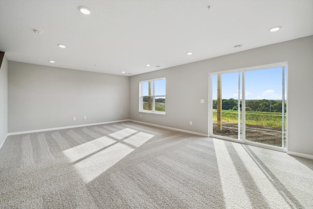 empty room featuring recessed lighting, light colored carpet, and baseboards