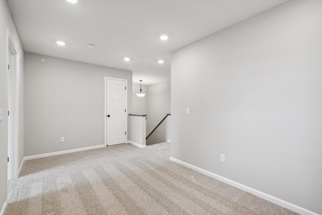 spare room with light carpet, recessed lighting, and baseboards