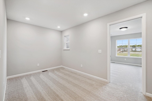 unfurnished room featuring light carpet, visible vents, and a wealth of natural light