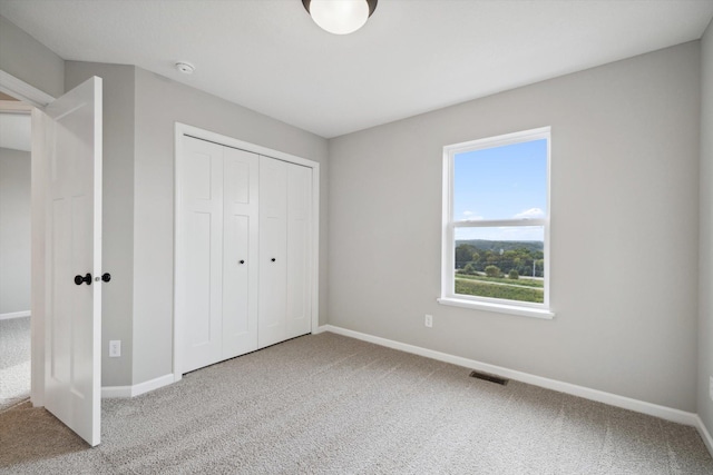 unfurnished bedroom featuring a closet, light carpet, visible vents, and baseboards