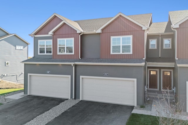 townhome / multi-family property featuring a garage, driveway, board and batten siding, and a shingled roof